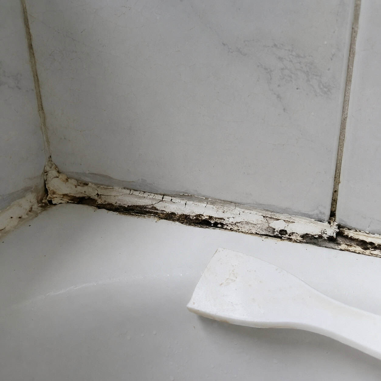 Cracked, Mildewed Caulk Around the Tub