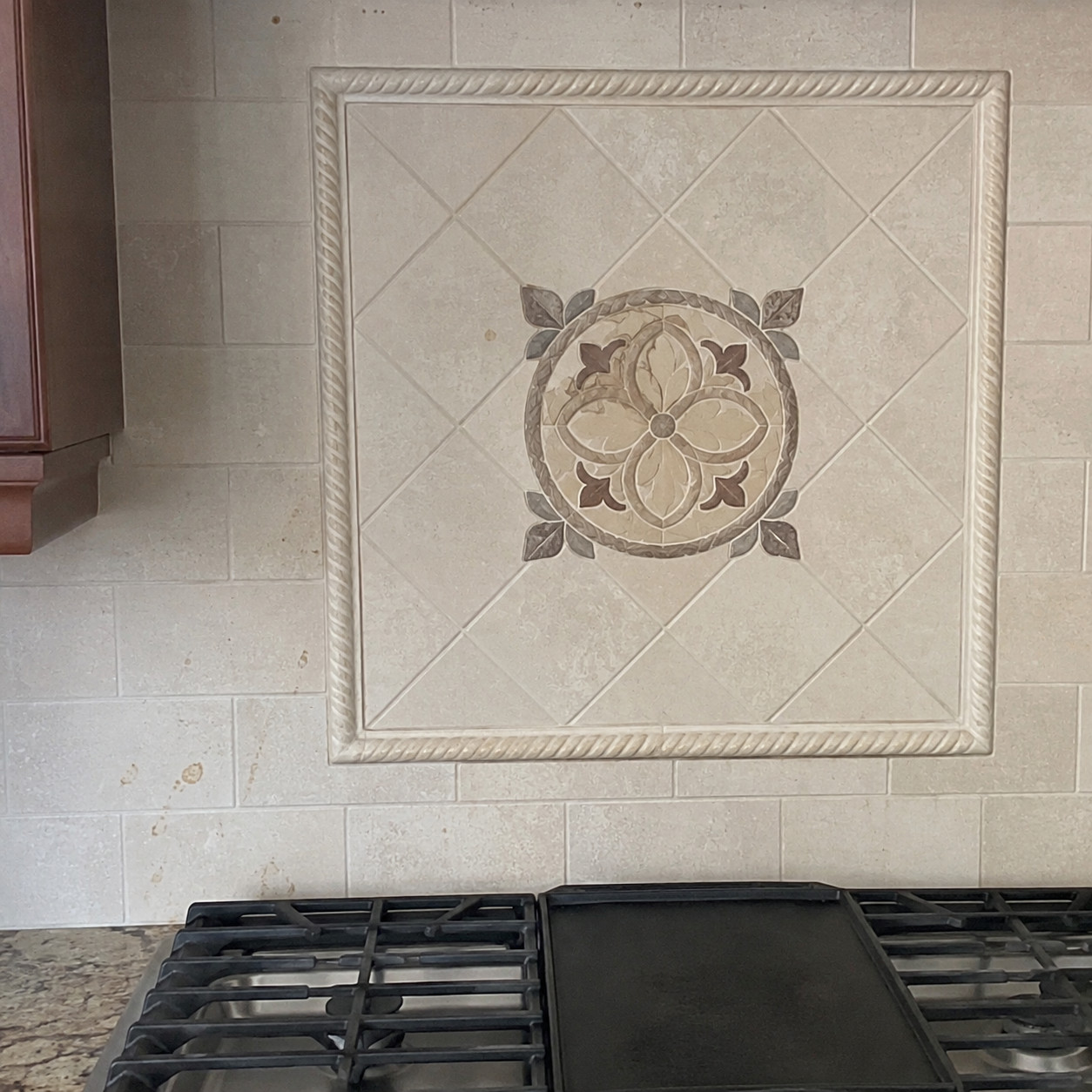Rope-trim tile medallion behind the cooktop